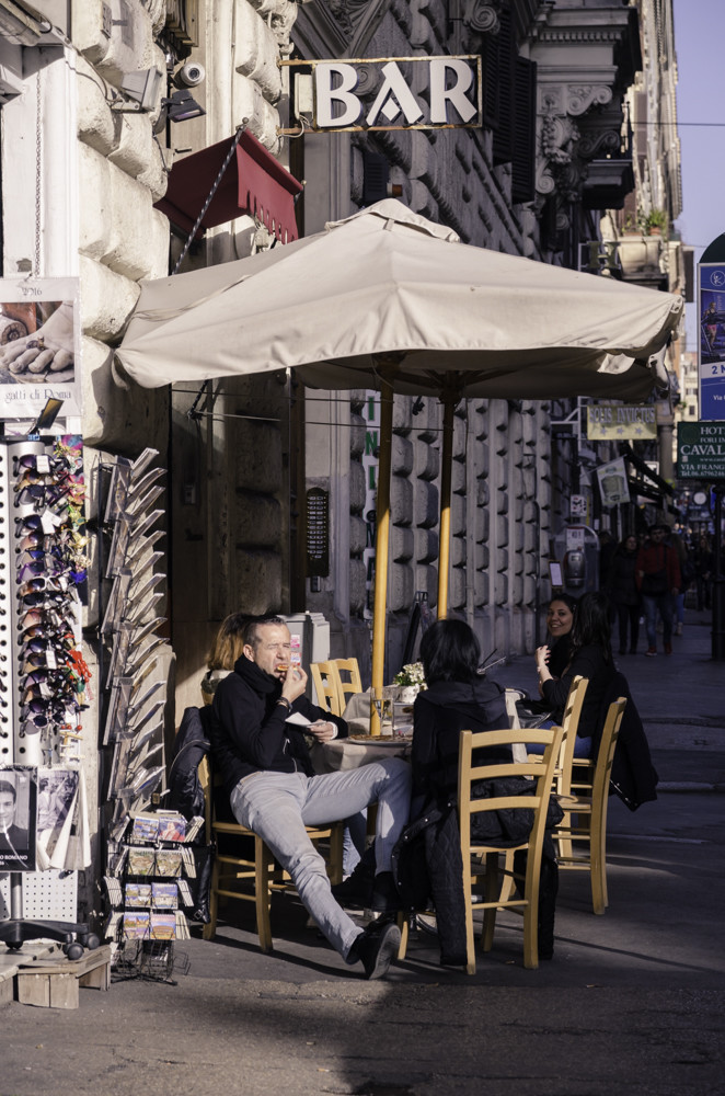 A man enjoying a piece of pizza at a bar in Monti